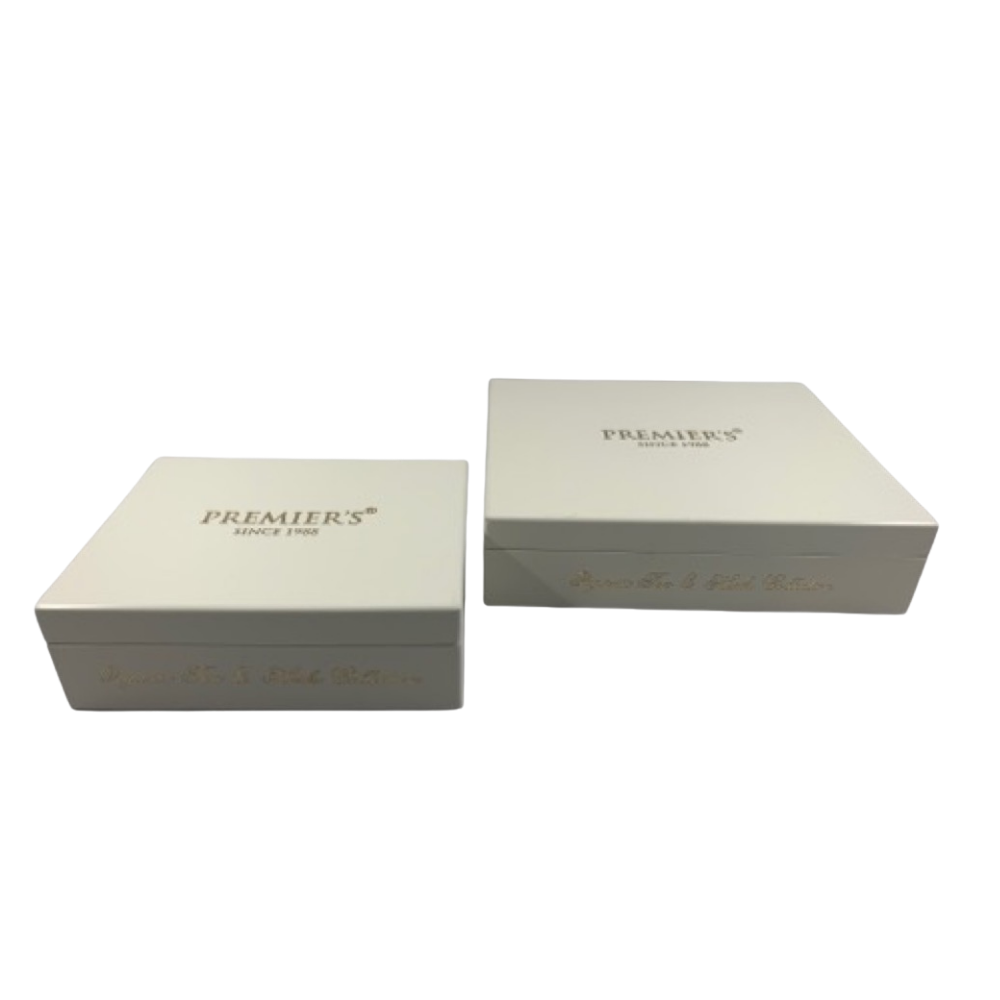 Two white rectangular boxes with gold writing on the sides and tops. The boxes are labeled PREMIERS SINCE 1906 and are placed against a plain white background.